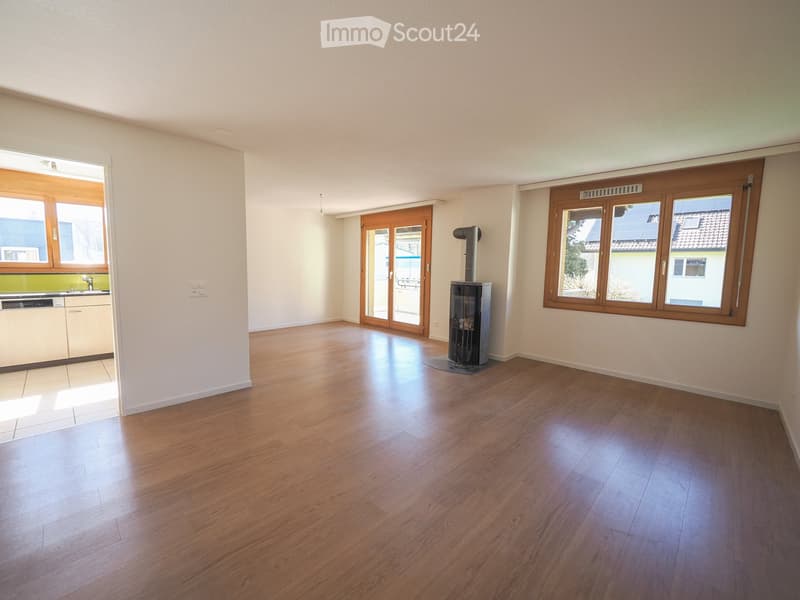 Empty room with wooden flooring, large windows, and a fireplace insert. The room is unfurnished with no visible furniture or equipment.