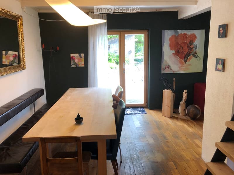 Dining area with wooden table, chairs, bench, artwork, and sculptures.