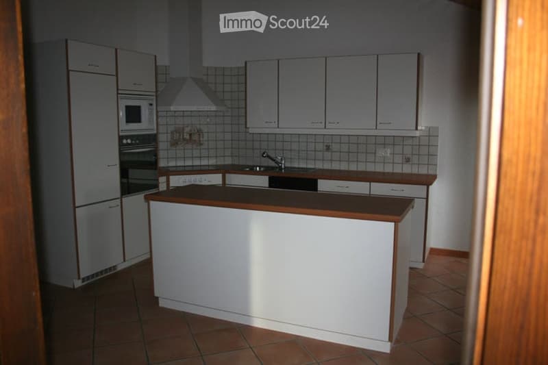 Modern kitchen with white cabinets, stainless steel appliances, and a central island with a wooden countertop.