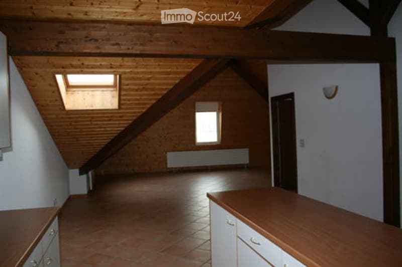 Empty attic room with wooden ceiling beams, exposed wooden walls, tiled floor, and a skylight window. No furniture or equipment present.