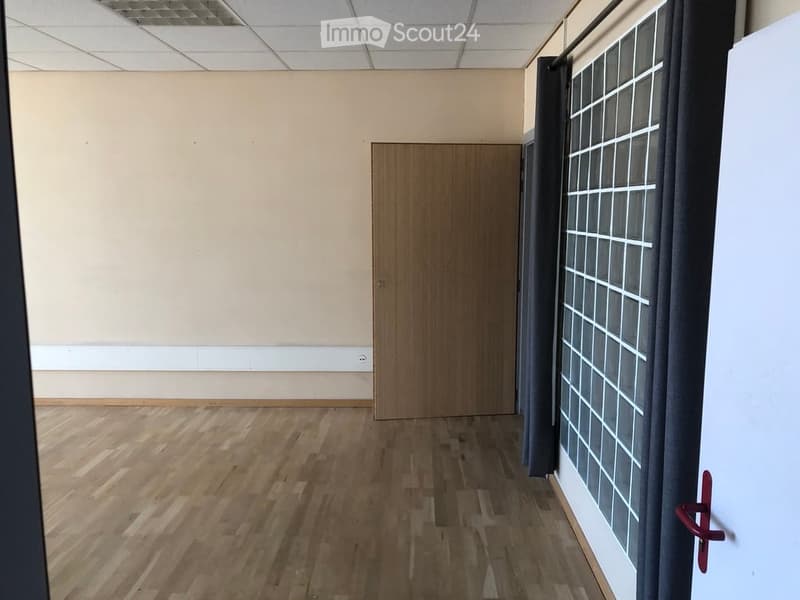 Empty room with wooden flooring, light-colored walls, and a single wooden door. No furniture or equipment is present.