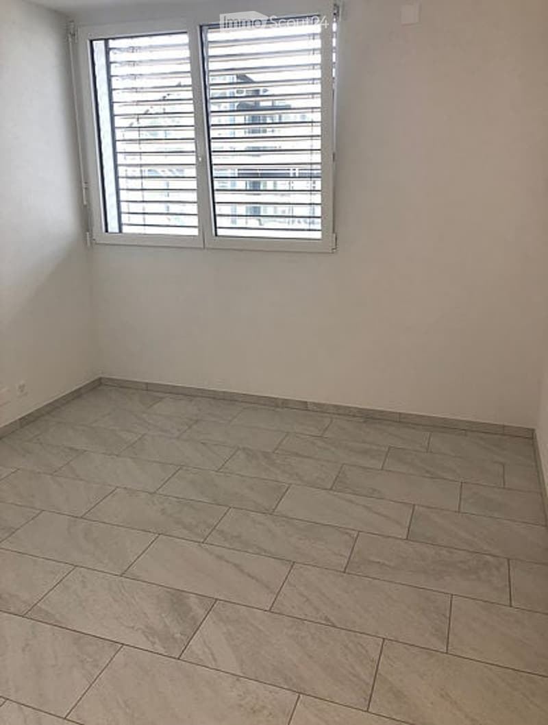 Empty room with tiled floor and large window with blinds. No furniture or equipment visible.