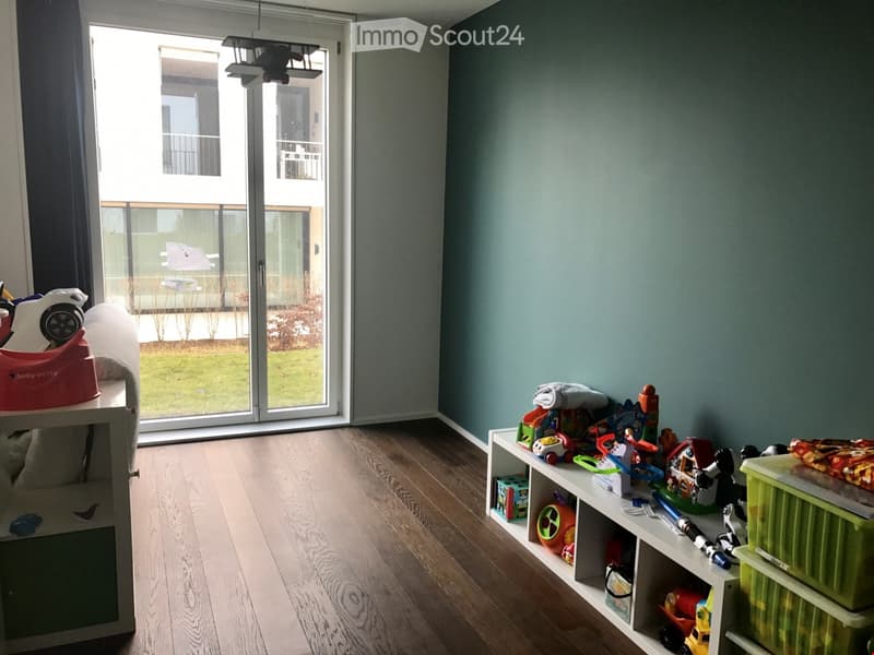 room with wooden floor, sliding glass door, green wall, toys on shelves, toys on floor