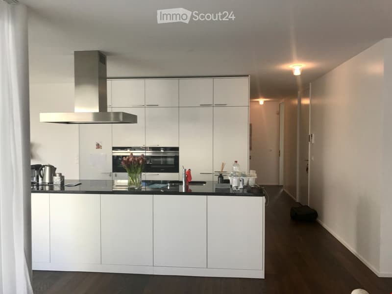 modern kitchen with white cabinets, black countertops, stainless steel appliances, and a large window