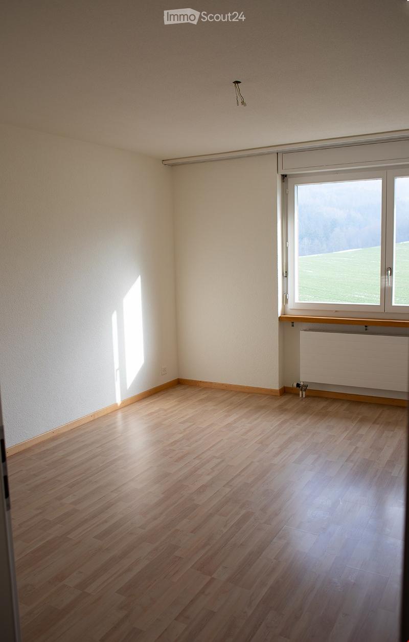 Empty room with wooden flooring, white walls, and large windows letting in natural light. No furniture or equipment present.