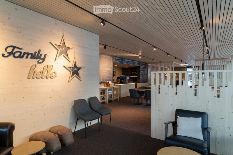 Modern, minimalist lounge area with wooden walls, grey carpet, and contemporary furniture including sofas, chairs, and small tables.