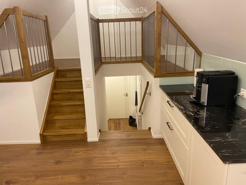 wooden stairs, white walls, wooden floor, white cabinets, black marble countertop, coffee machine