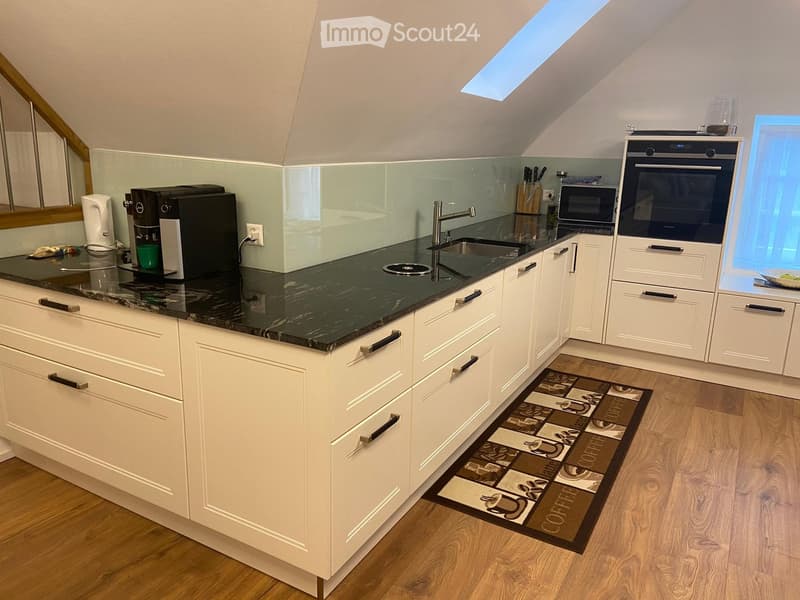 modern kitchen with white cabinets, black granite countertop, stainless steel sink, coffee machine, microwave, oven, wooden floor, skylight
