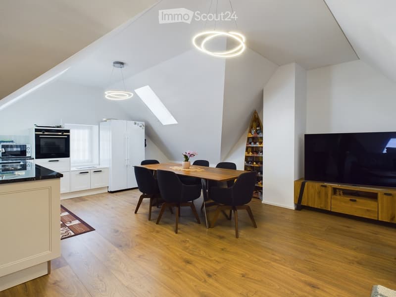 Dining area with wooden table, black chairs, white kitchen, microwave, oven, refrigerator, TV, wooden entertainment center, wooden flooring, white walls, ceiling lights