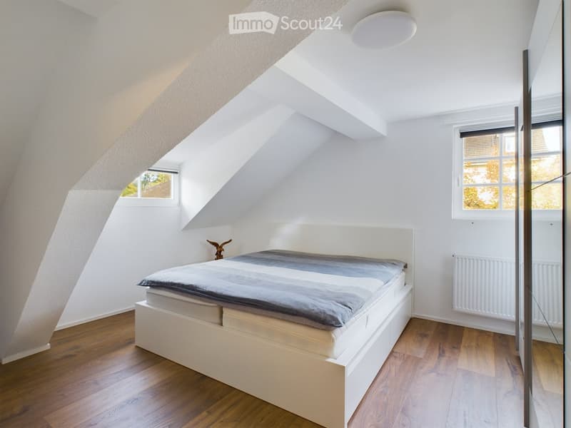 white walls, wooden floor, white bed with storage drawers, white ceiling, two small windows, white radiator