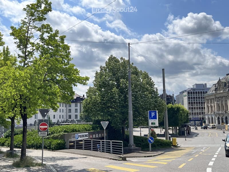 Urban street scene with parking signs, traffic signs, trees, and buildings in the background.