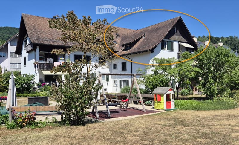 A two-story house with a brown roof and white walls, surrounded by a well-maintained garden with a swing set, a small playhouse, and a patio area.