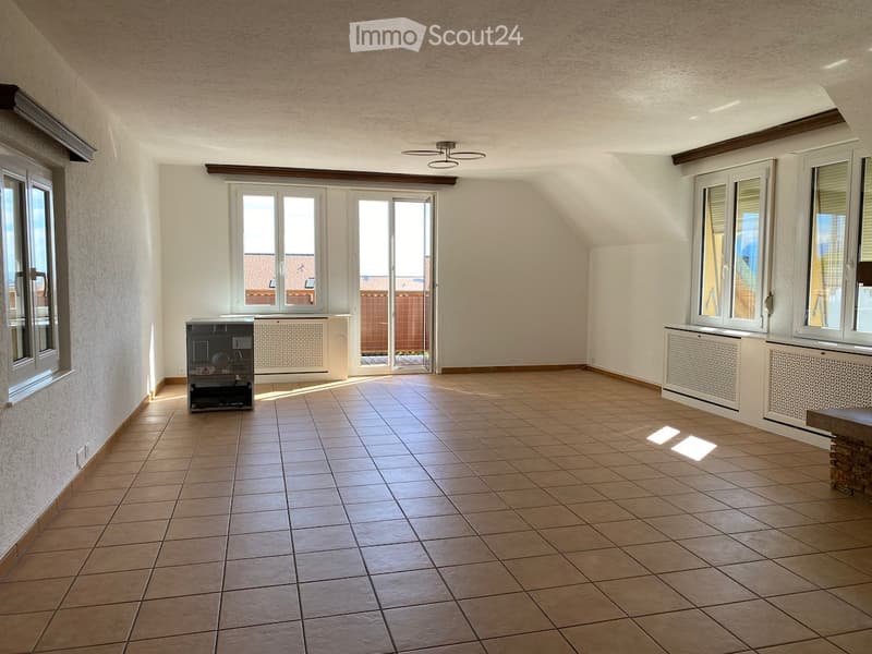 Empty room with tiled floor, white walls, large windows, and a sliding glass door leading to a balcony.