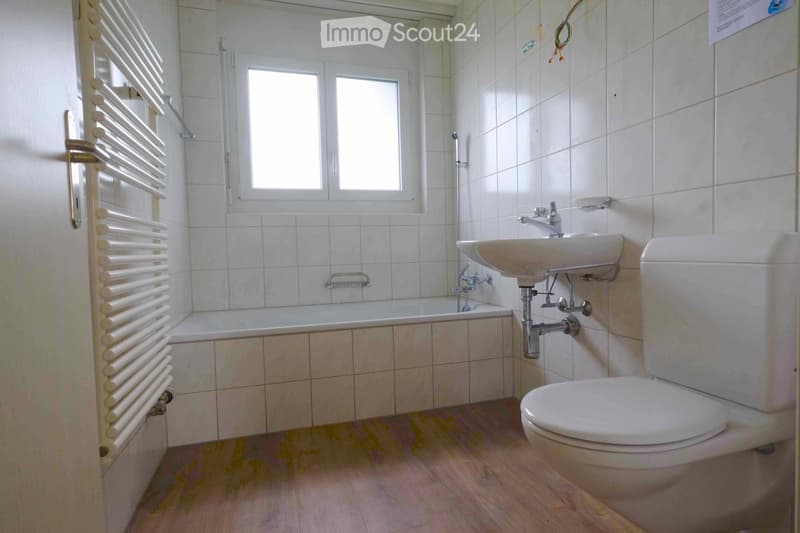 Bathroom with white tiled walls, a bathtub, a toilet, a sink with a faucet, and a white radiator on the left side.
