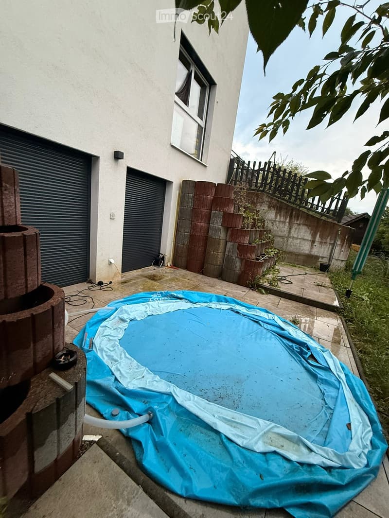 Backyard area with a covered inflatable pool, brick planters, a garage, and a fence.