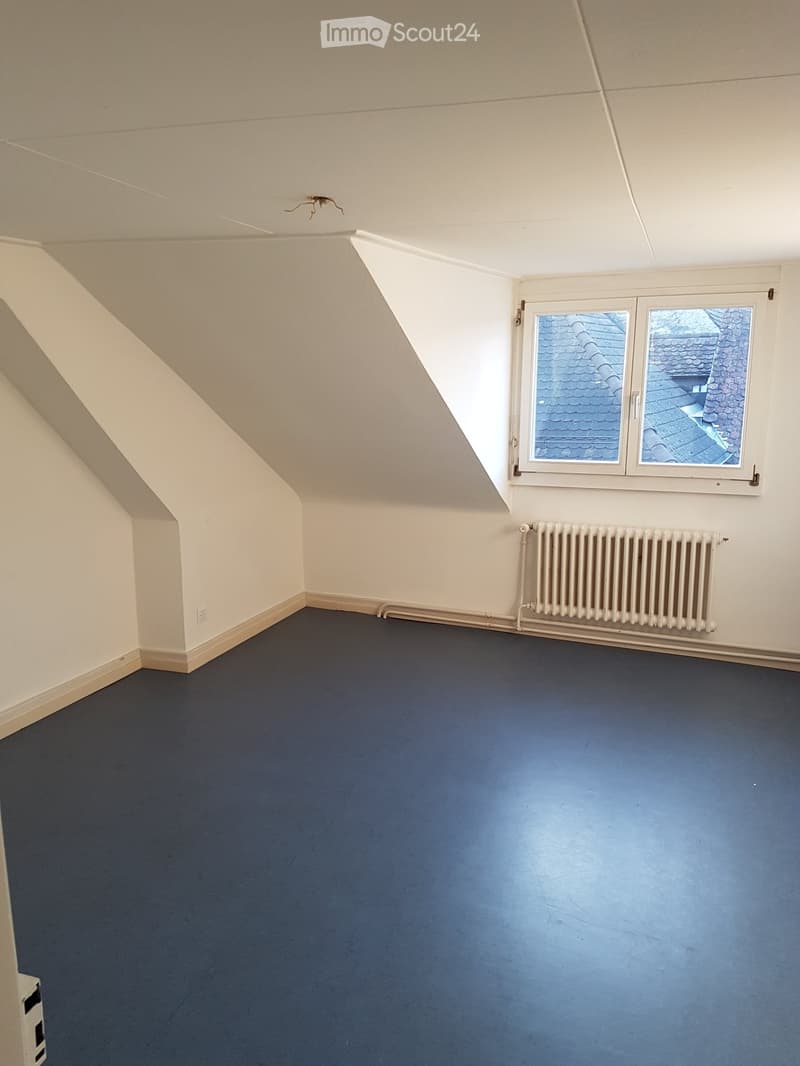 empty room, white walls, blue floor, slanted ceiling, white radiator, window