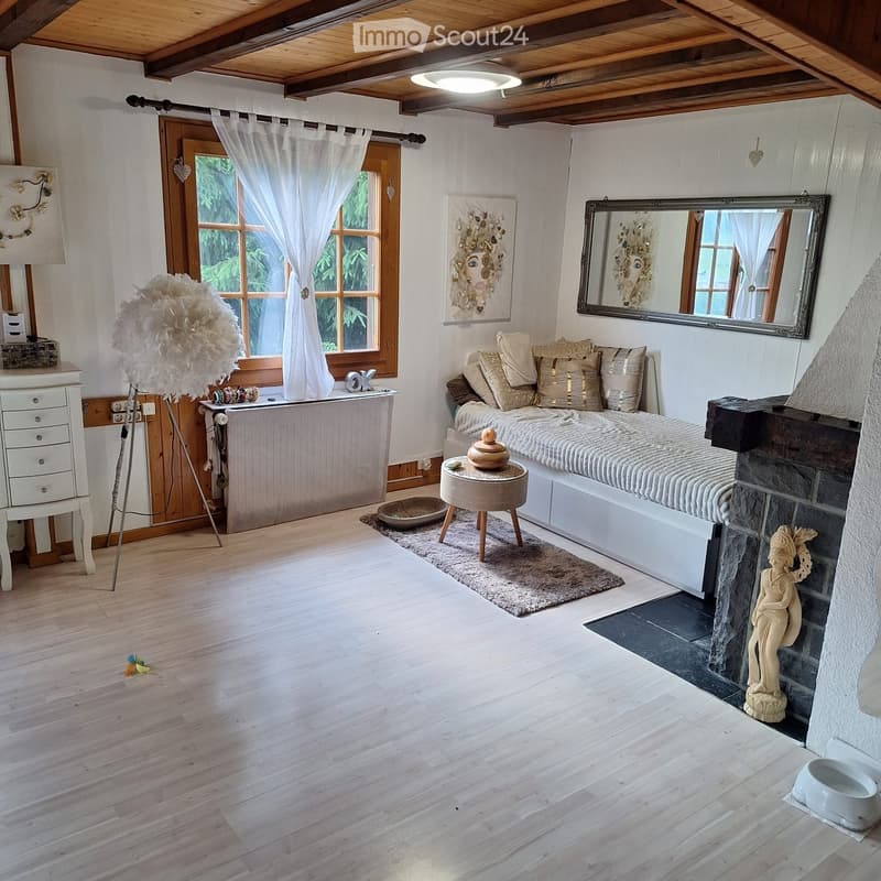 Cozy bedroom with wooden floors, a large bed with pillows, a fireplace, a mirror, a nightstand, a small table, and decorative items.