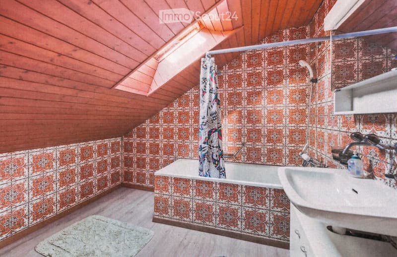Bathroom with wooden ceiling, patterned tiles, bathtub, sink, and shower curtain.