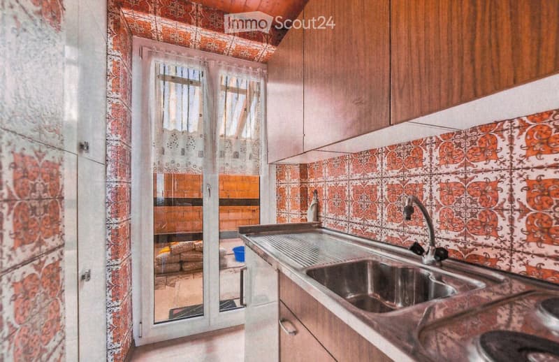 Kitchen with stainless steel sink, faucet, wooden cabinets, and patterned tiles.