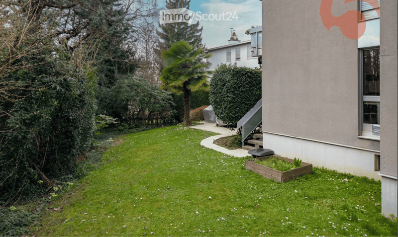 Well-maintained garden with a lawn, small raised bed, and a pathway leading to a house entrance.
