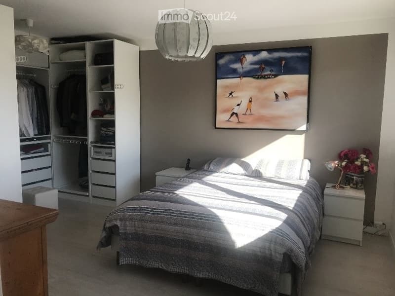 Bright bedroom with a large bed, nightstands, wardrobe, and a painting on the wall.