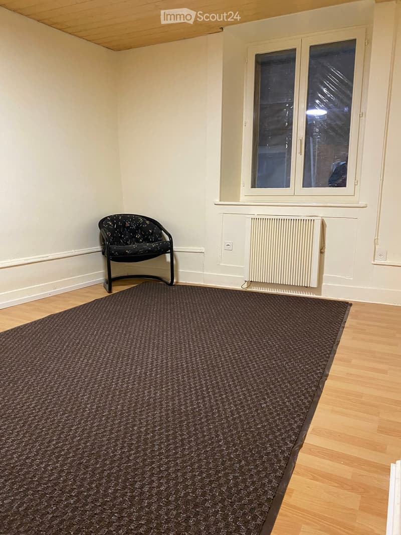 Empty room with hardwood floor, radiator, window, and a chair