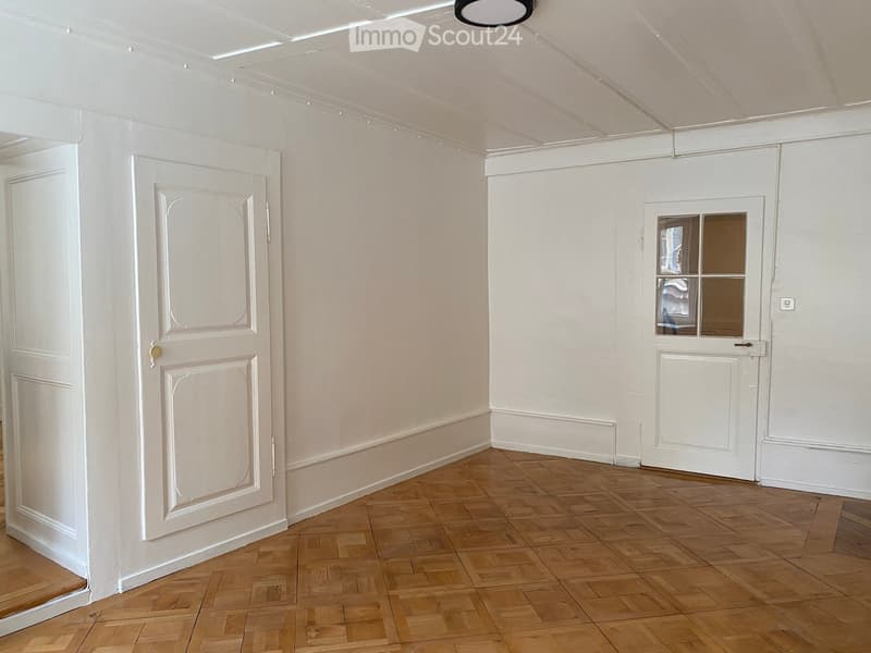 empty room, white walls, wooden floor, two doors, one with window