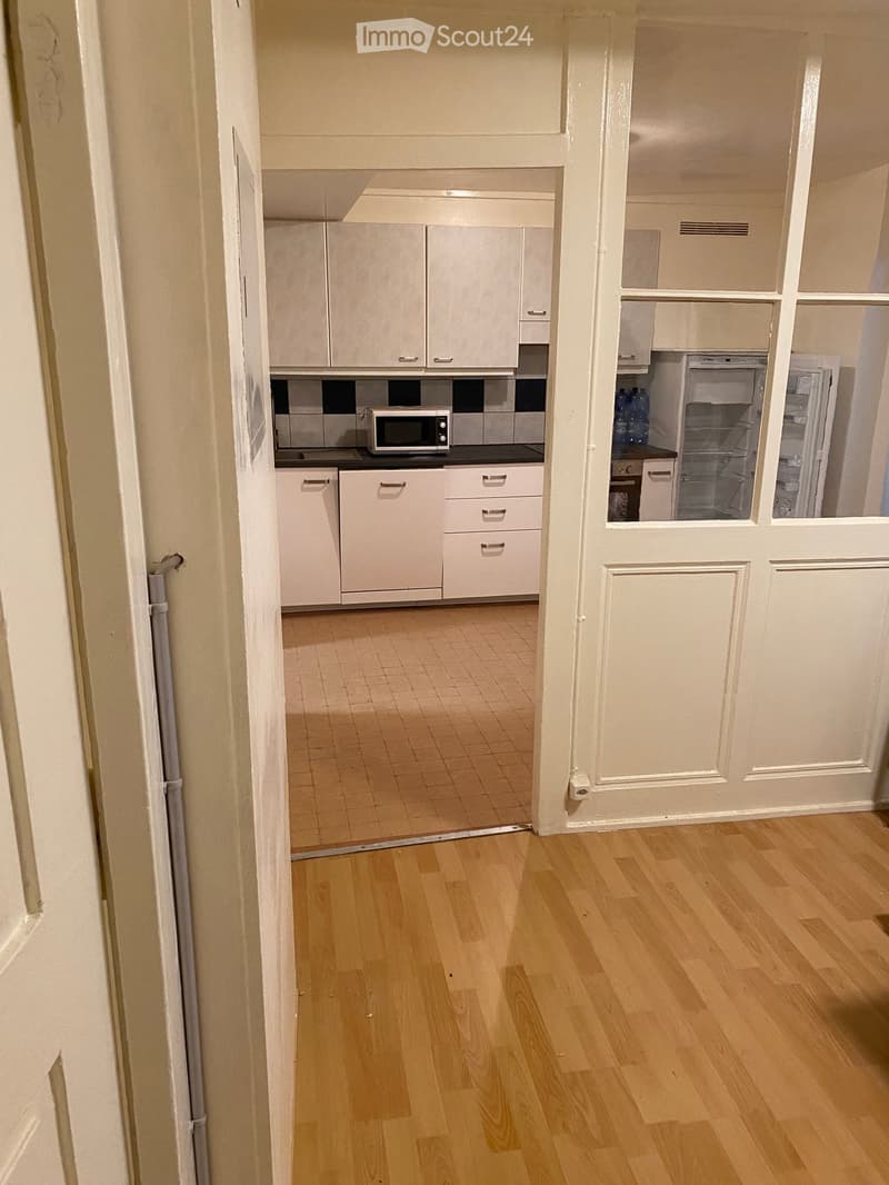 Empty kitchen with white cabinets, tiled floor, microwave, refrigerator, and sink.