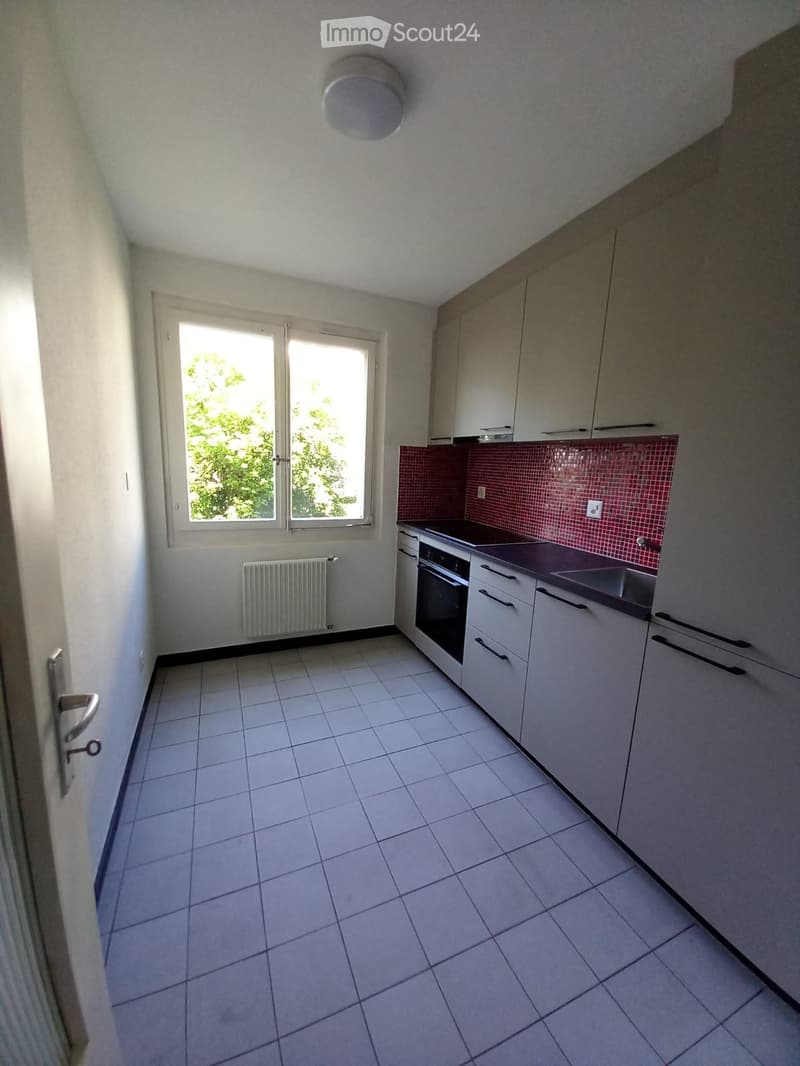 Modern kitchen with white cabinets, a built-in oven, a sink, and a radiator near the window.