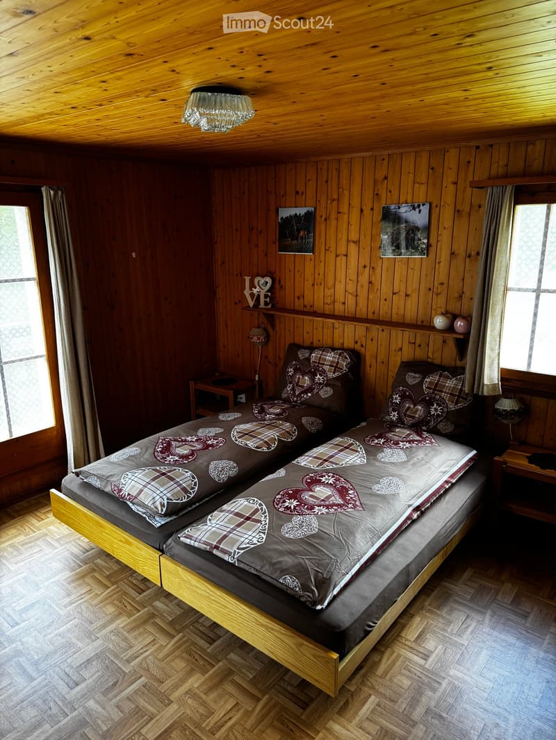 Cozy wooden bedroom with a double bed, nightstands, lamps, and artwork on the walls.