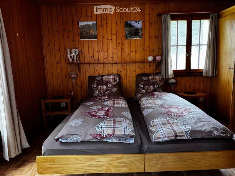 Cozy wooden bedroom with two single beds, matching bedding, nightstands, lamps, and decorative wall art.