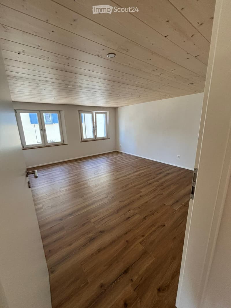 Empty room, hardwood floors, white walls, two windows, two power outlets on the wall