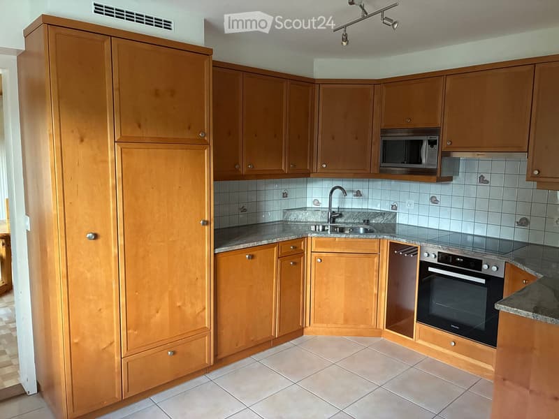 Modern kitchen with light wooden cabinets, granite countertop, stainless steel sink, and built-in oven and microwave.