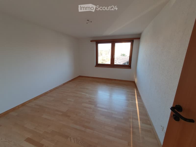 Empty room with wooden flooring, white walls, and a single window with wooden frame. No furniture or equipment present.