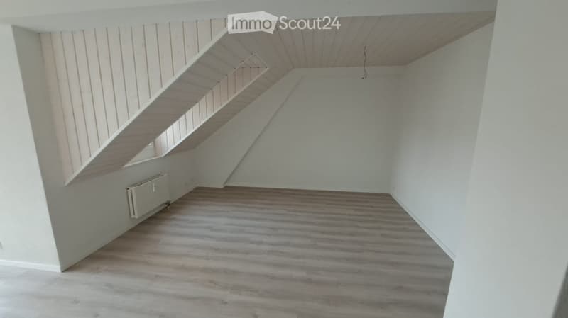Empty room with wooden flooring, white walls, and a staircase leading to an upper level. No furniture or personal items are present.