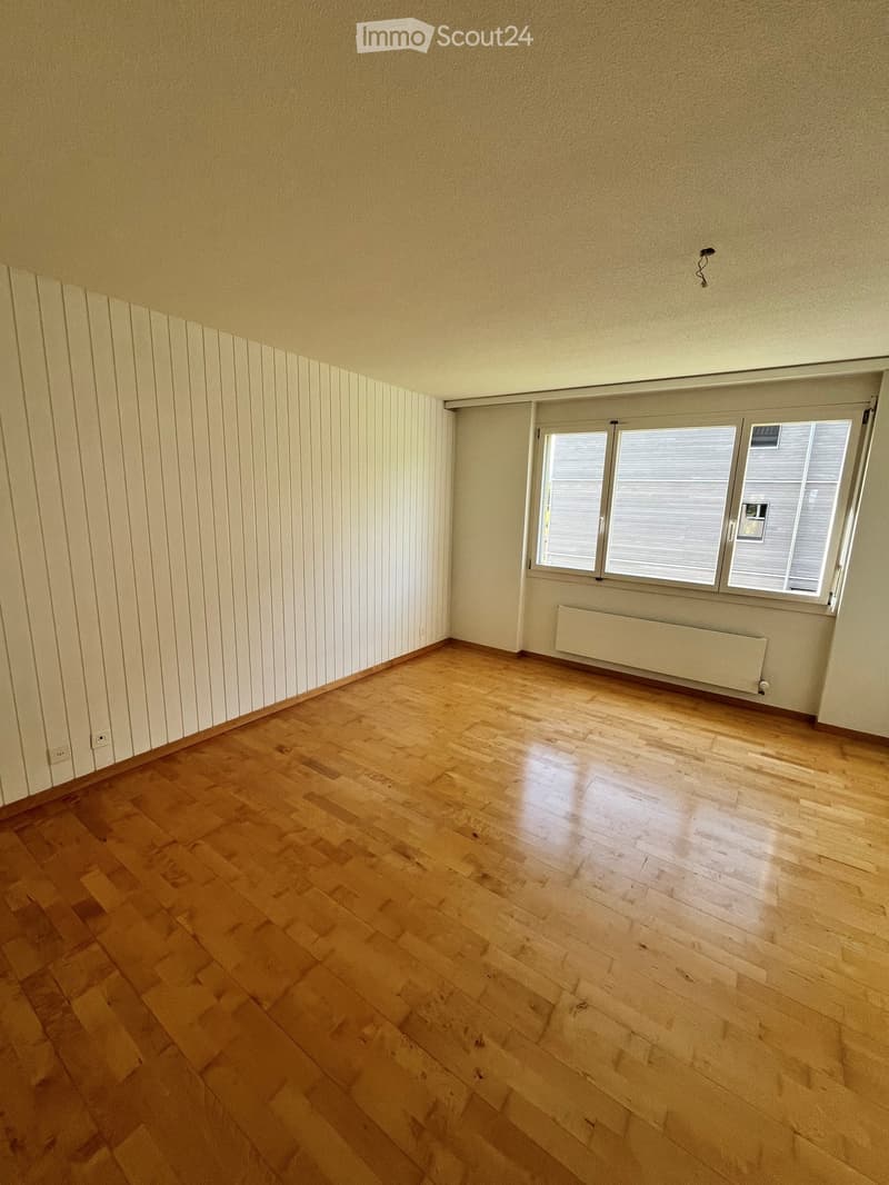 Empty room with wooden flooring, white walls, and a large window with blinds. No furniture or equipment is present.