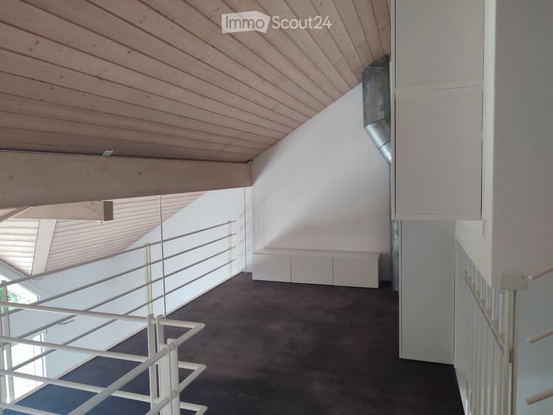 Modern hallway with wooden slatted ceiling, white walls, dark concrete floor, and white metal railings leading to an open area.