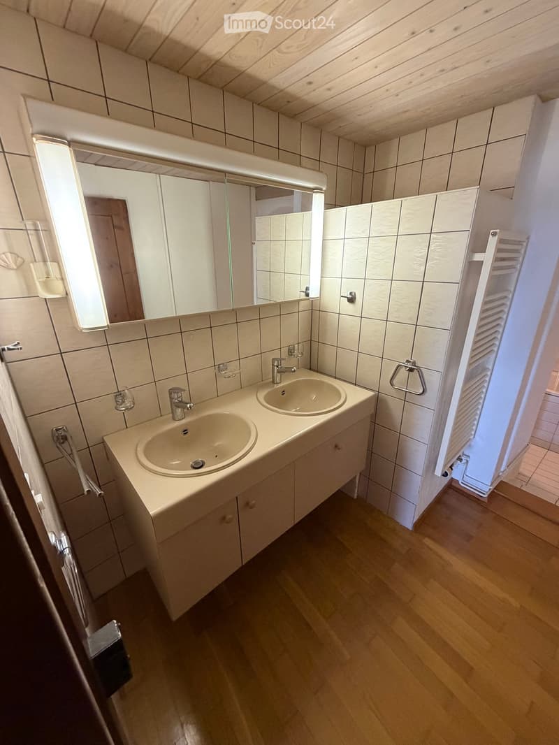 Bathroom with two sinks, mirrors, and wooden flooring.