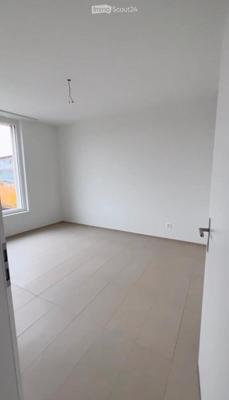 Empty room with white walls, tiled floor, and a single window letting in natural light. No furniture or personal items are present.
