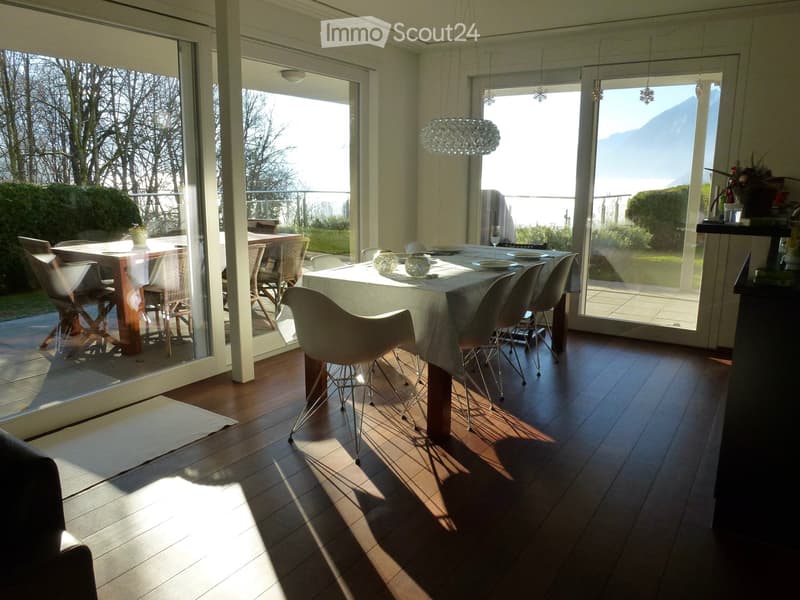 Bright dining area with large windows offering a scenic mountain view, featuring a wooden dining table, modern chairs, and decorative items.