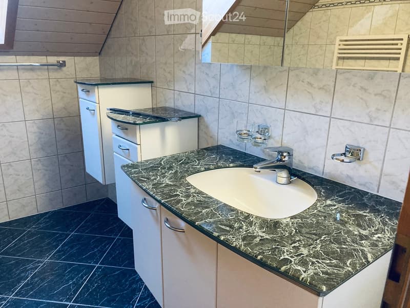 Modern bathroom with a marble countertop, white sink, chrome faucet, and white cabinets with glass tops.