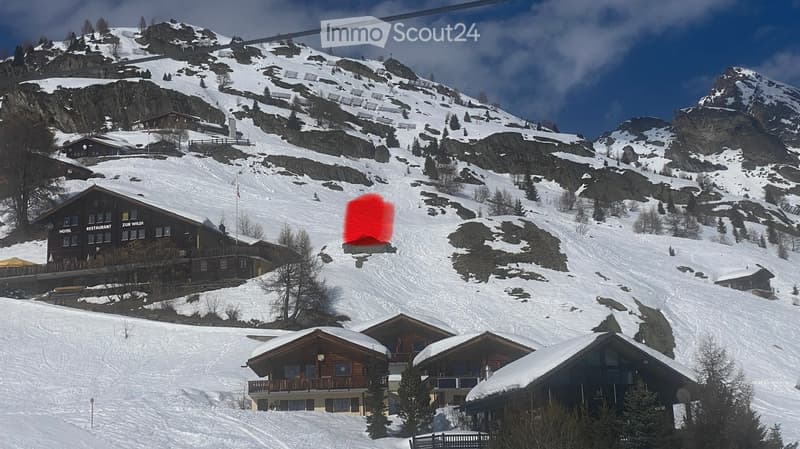 A snowy mountain landscape with several houses and a ski slope, featuring a ski lift and a red overlay on the slope.