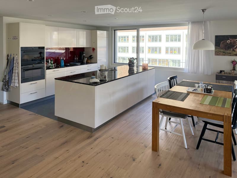 modern open plan kitchen, wooden dining table, island countertop, white cabinetry, black countertops, large window, contemporary fixtures, minimalist decor