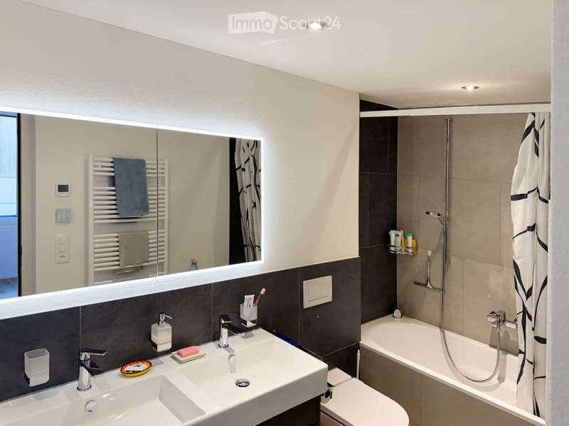 modern bathroom with bathtub, double sink, shower, and white tiled walls