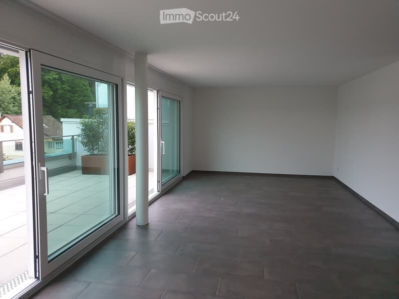 Empty room with large glass sliding doors leading to a balcony, tiled floor, and white walls.