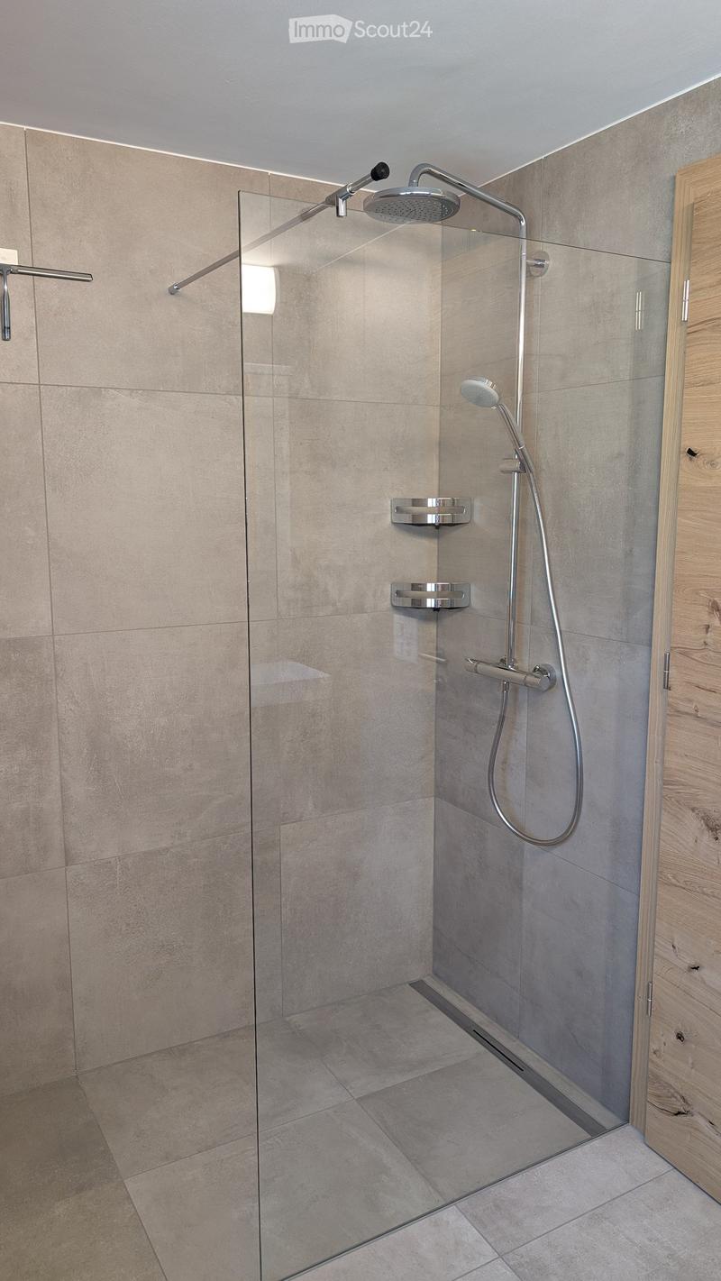 Modern shower area with a glass enclosure, multiple showerheads, and sleek controls.