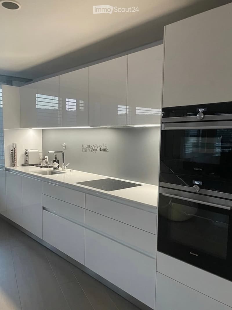modern kitchen with white cabinets, black induction hob, built-in oven, sink, faucet, and a window with blinds