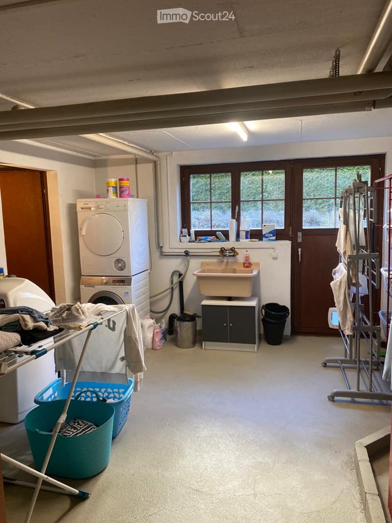 Functional laundry room with a washing machine, sink, cabinet, laundry baskets, and a drying rack.