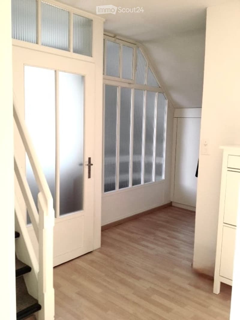 Empty room with wooden flooring, white walls, and large frosted glass windows. No furniture or equipment visible.