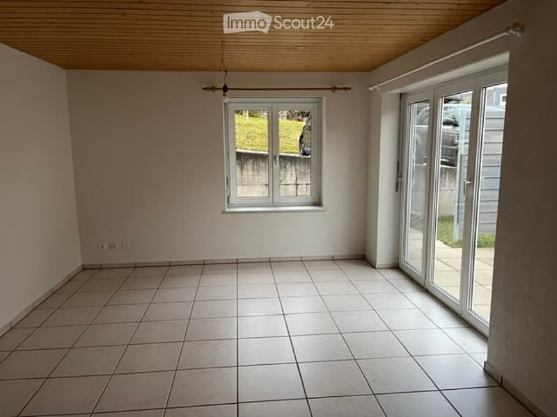 Empty room with tiled floor, white walls, large window, and sliding glass door leading to an outdoor area.